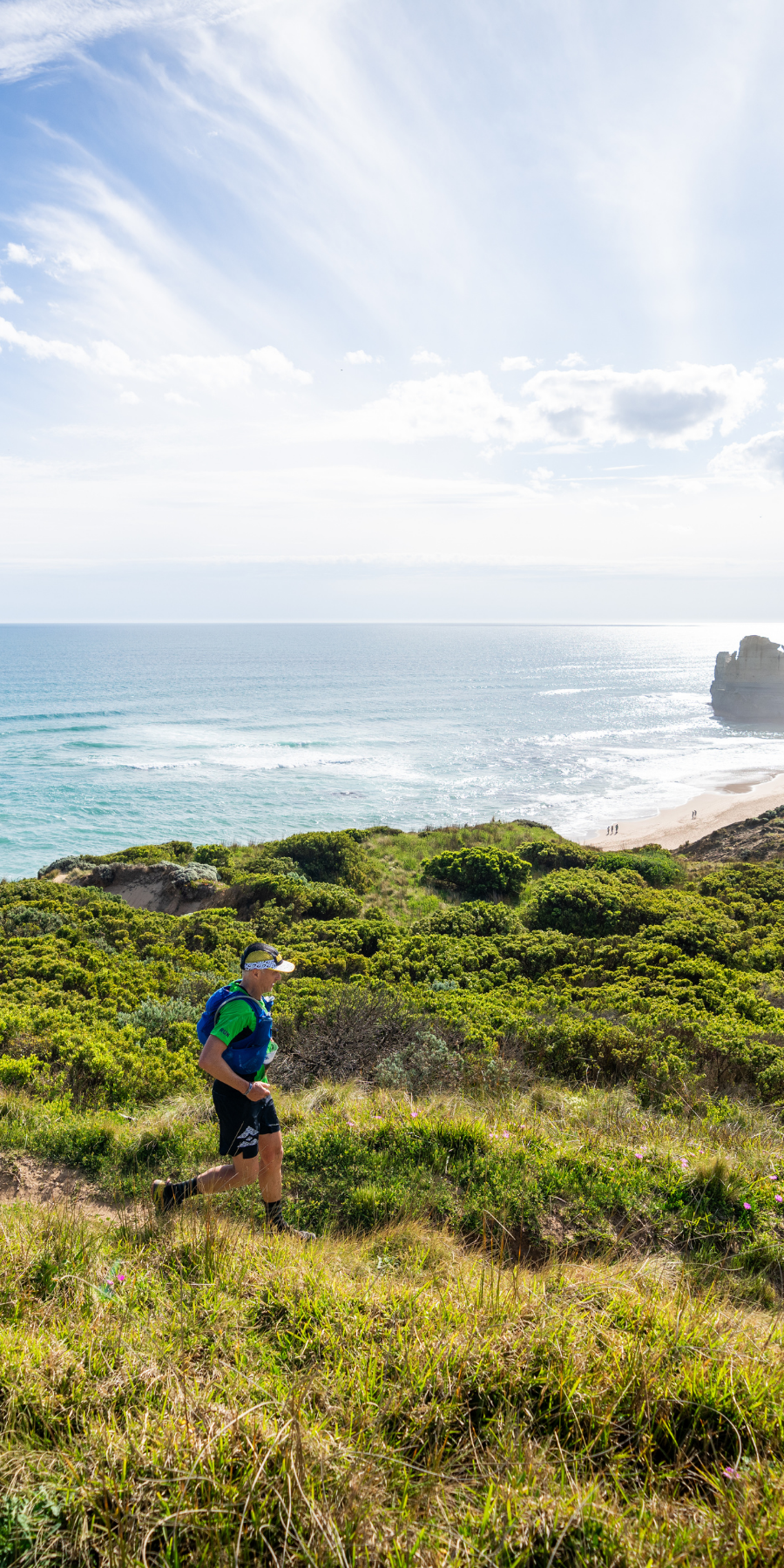 Person running on a grassy hill with ocean view